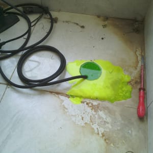 כלי עבודה וצינור ליד כתם נוזל ירוק על הרצפה