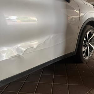 נזק לדלת רכב לבנה עם שריטות ושקעים