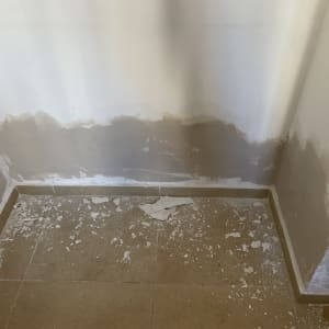 קיר עם תיקוני טיח ופסולת על הרצפה