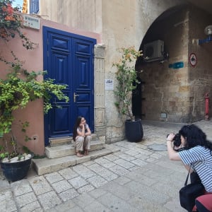 צלמת מצלמת אישה יושבת על מדרגות ליד דלת כחולה