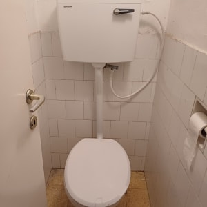 אסלה עם מיכל הדחה לבן וצינור חיבור