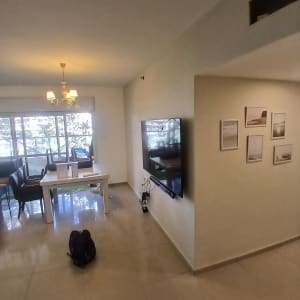 חדר מגורים עם טלוויזיה על הקיר ושולחן אוכל