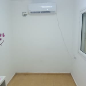 מזגן מותקן על קיר לבן עם כבל חשמל