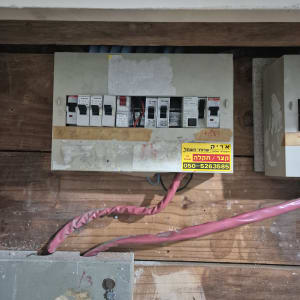 לוח חשמל עם כבלים אדומים ותגית צהובה