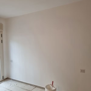 קיר צבוע עם דלי צבע ומברשת על הרצפה