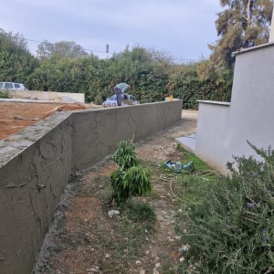 אדם צובע קיר בטיח אפור בחוץ