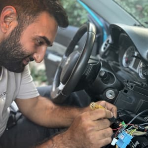 אדם מתקן חיווטים במערכת רכב עם מברג