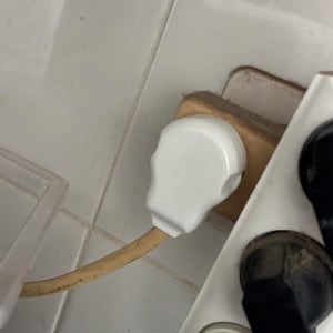 תקע חשמלי לבן מחובר לשקע על קיר לבן