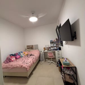 חדר שינה מסודר עם מיטה, שולחן עבודה ומדפים