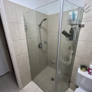 מקלחון זכוכית עם ראש מקלחת ומדף מוצרים