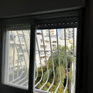 חלון עם סורגים ונוף של בניינים ועצים