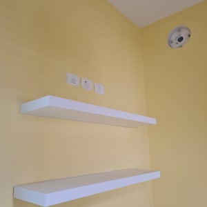 קיר צבוע בצהוב עם מדפים לבנים