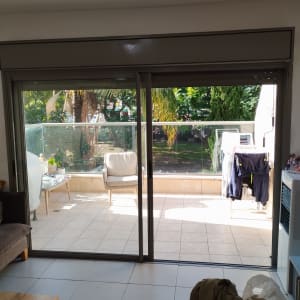 תריסים חומים על חלון זכוכית גדול בסלון