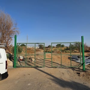 שער חשמלי ירוק עם רכב עבודה בצד שמאל