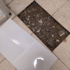 רצפה עם אריחים שבורים ותיקון אריח חדש