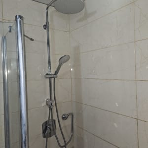 מערכת מקלחת וראש טוש מותקנים על קיר אריחים בחדר רחצה