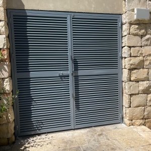 שער מתכת אפור עם תריסים בין קירות אבן