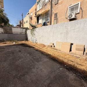 חצר עם קיר בטון וערימת בלוקים