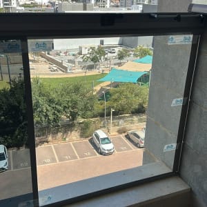 חלון זכוכית עם נוף לבניינים גבוהים וחניון