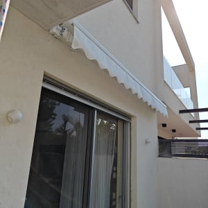 סוכך לבן מותקן מעל חלון זכוכית גדול