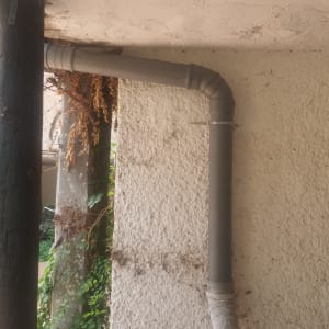 צינור פלסטיק אפור מחובר לקיר עם תושבת מתכת