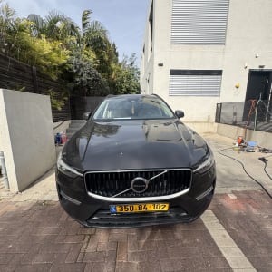 רכב שחור חונה ליד בית עם צינור מים