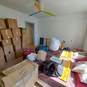 חדר עם קופסאות קרטון, מיטה ומזוודות