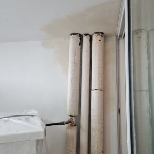 צינורות ישנים עם צבע מתקלף על קיר לבן