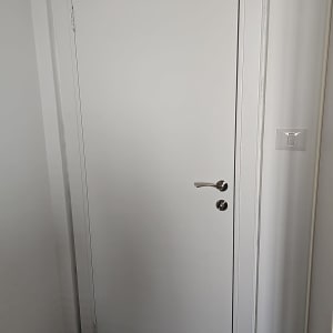 דלת לבנה עם ידית כסופה ומתג ליד