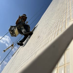 אדם תלוי על חבלים צובע קיר חיצוני