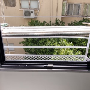 חלון פתוח עם מסגרת שחורה ומעקה מתכת לבן