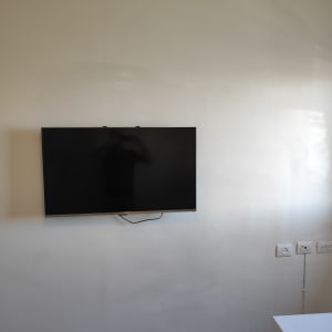 טלוויזיה תלויה על קיר עם כבלים חשמליים