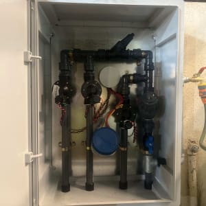 מערכת השקיה בתוך ארון פתוח עם צינורות ושסתומים