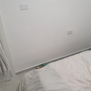 קיר צבוע עם שקע חשמל ומיטה