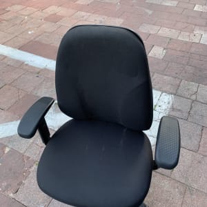 כיסא משרדי שחור עם משענות ידיים על מדרכה