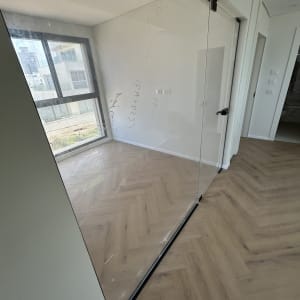 חדר עם רצפת פרקט ודלת זכוכית נקייה