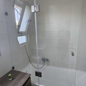 מקלחון זכוכית עם אמבטיה וחלון פתוח