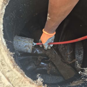 יד עם כפפה כתומה מחזיקה צינור בתוך ביוב