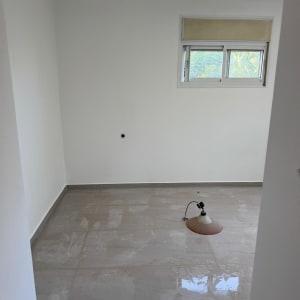 חדר ריק עם קירות צבועים בלבן ומנורה על הרצפה