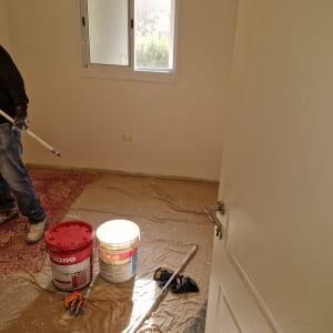 חדר עם דלי צבע, מברשת ורצפה מכוסה בניילון