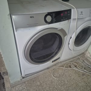מייבש כביסה סטנדרטי מסוג AEG ומכונת כביסה בחדר שירות