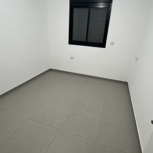 חדר ריק עם רצפת אריחים וקיר לבן