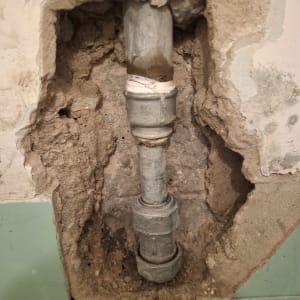 צינור חשוף בקיר עם טיח מתקלף