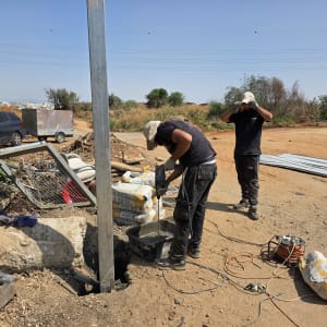 עובדים מתקינים שער חשמלי באתר בנייה