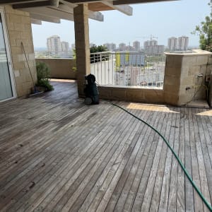 מרפסת עץ עם צינור מים ונוף עירוני ברקע