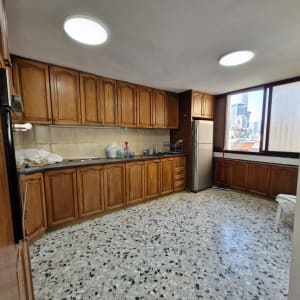 מטבח עם ארונות עץ, מקרר וחלון גדול