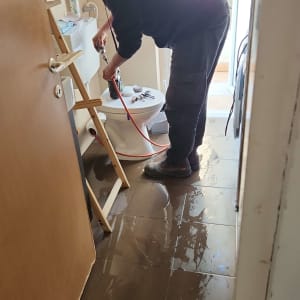 אדם עובד על תיקון שירותים עם כלים וצינור