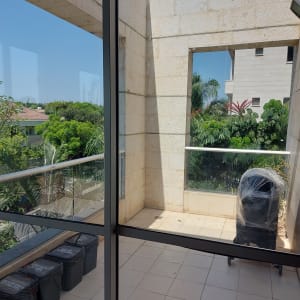 חלון זכוכית עם נוף של מרפסת וצמחייה