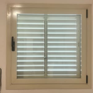 תריסים לבנים סגורים במסגרת חלון לבנה