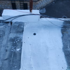 איטום גג עם חומר לבן סביב צינור מתכת
